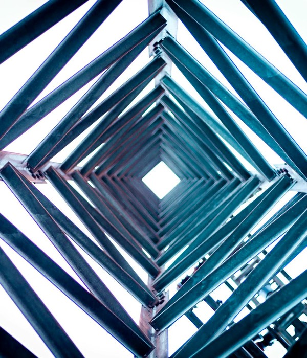 Artistic view looking up through a geometric steel tower against a bright sky.